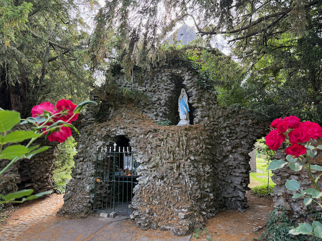 A small grotto in the beguinage garden with a statue of Mary. It’s a quiet, shady spot where people leave candles and take a moment to reflect.