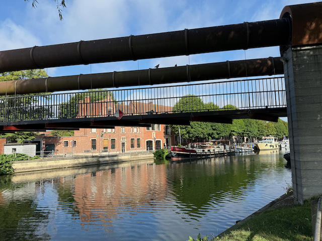 This is a very cool lifting bridge for pedestrians and bikes.  The cables wrap around those tubes, which twist to raise the bridge