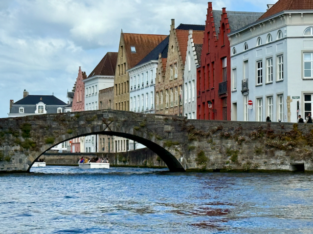 Under ancient arches and past painted facades, the boat glides on. Bruges reveals its story in rooftops and reflections—each gable a chapter, each ripple a whisper from centuries past.